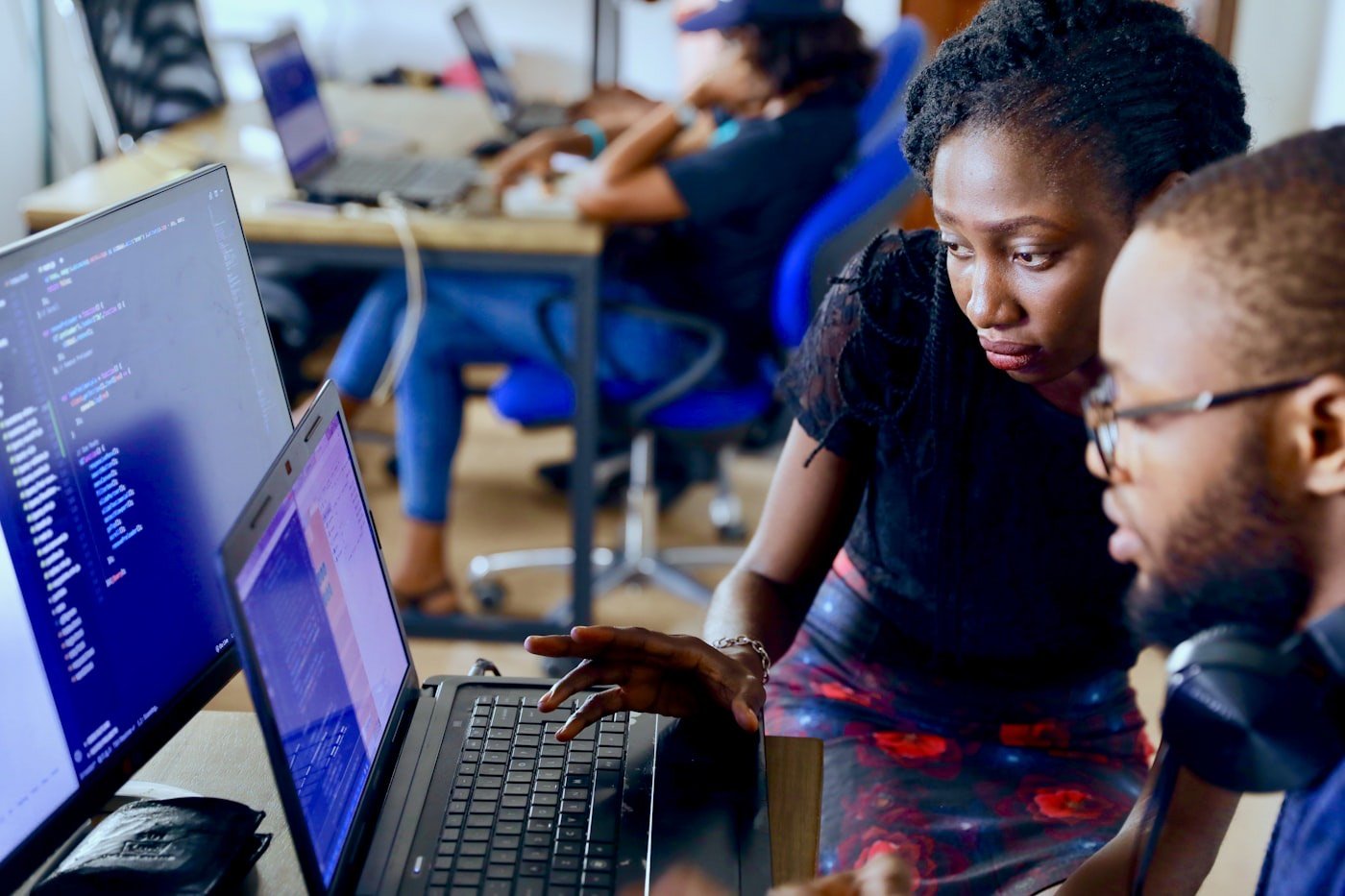Two African developers reviewing code together at a laptop in a Lagos workspace