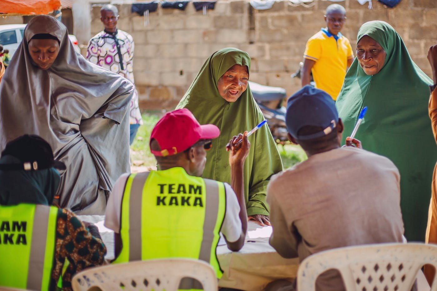 A community outreach team in hi-viz vests engaging with residents at a meeting in Kaduna, Nigeria — the kind of mission work Dibia Solutions equips NGOs to deliver